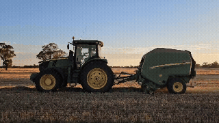 John Deere Baler, baling hay on dusk